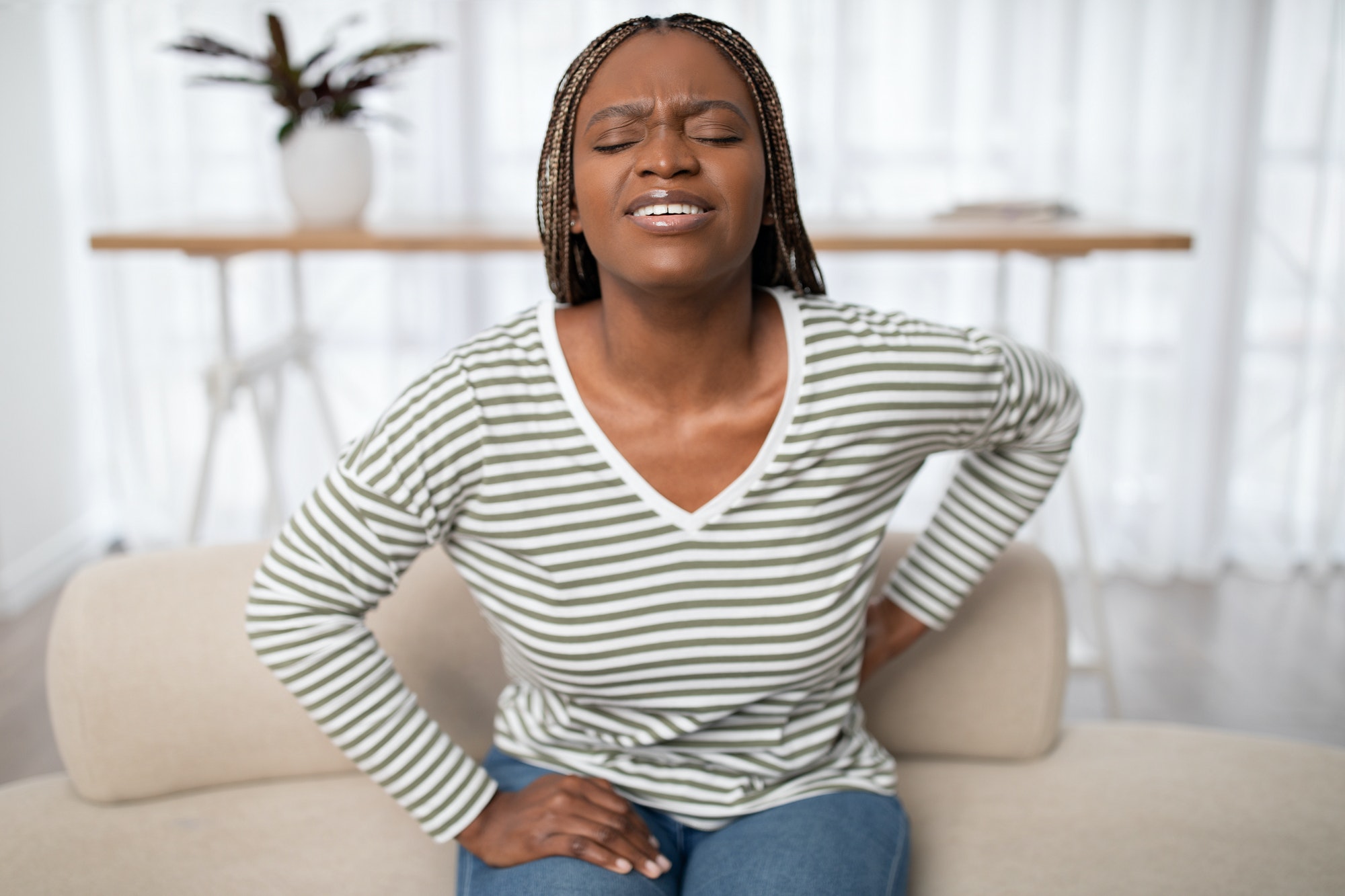 Sad african american woman touching back, have pain