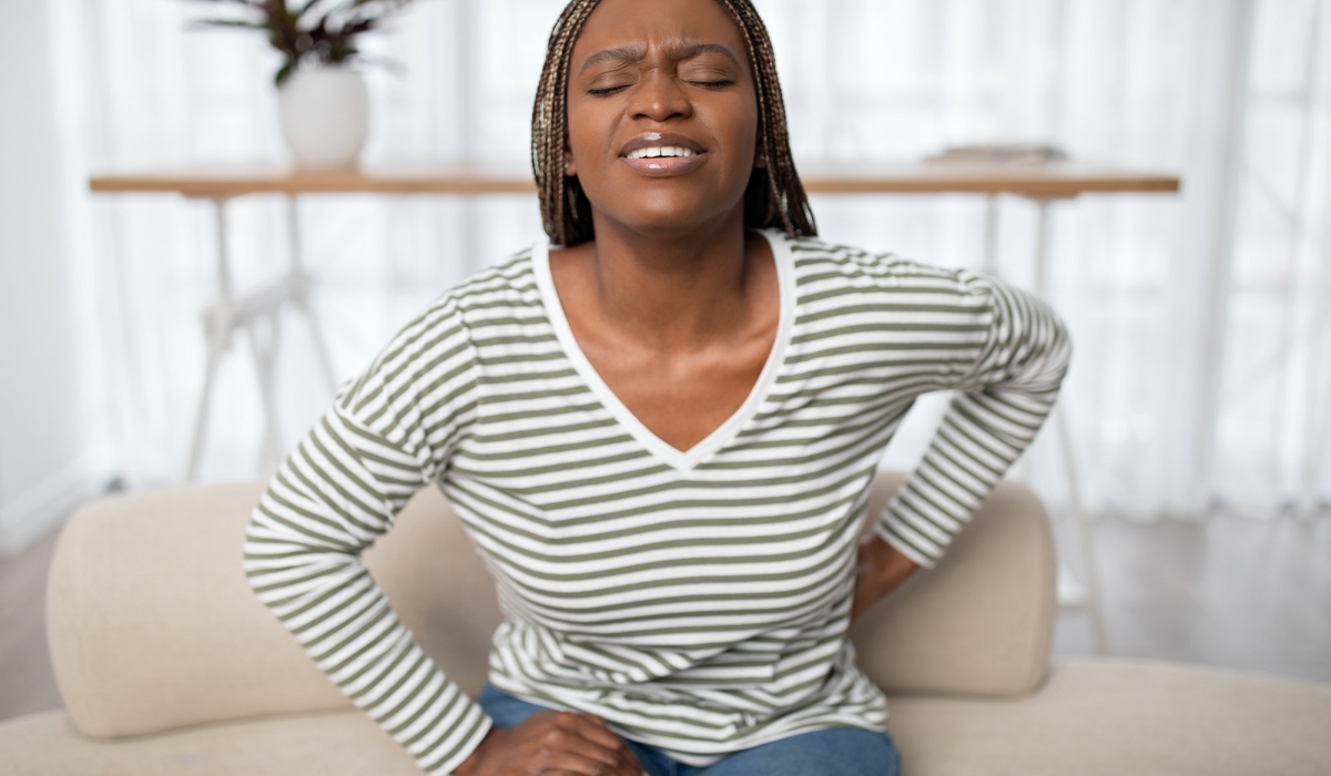 Sad african american woman touching back, have pain